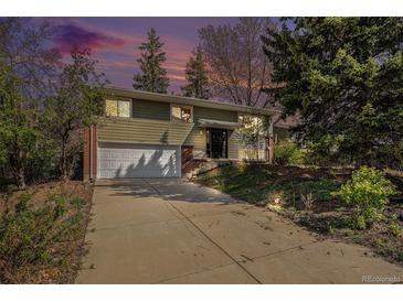 Charming two-story home with mature trees, a paved driveway, and an attached two-car garage at 1244 S Wright St, Lakewood, CO 80228