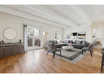 Bright and airy living room featuring hardwood floors, modern decor, and sliding glass doors to a private balcony at 9700 E Iliff Ave # G70, Denver, CO 80231