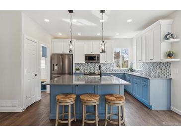 Bright, modern kitchen featuring a large island, stainless steel appliances, and stylish blue and white cabinetry at 1534 Stanley Dr, Erie, CO 80516