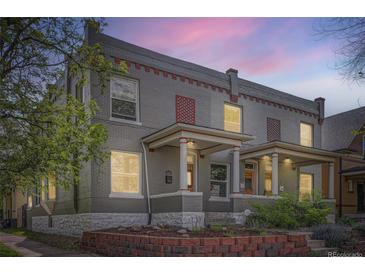 Charming grey brick duplex home with a well-maintained lawn, front porch, and colorful architectural details at 2564 N Emerson St, Denver, CO 80205