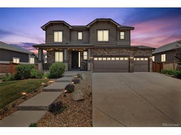 Inviting two-story home featuring a stone facade, three-car garage, and manicured landscaping at 76 N Ider St, Aurora, CO 80018