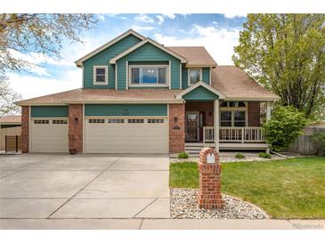 Charming two-story home featuring a well-manicured lawn, front porch, and three-car garage at 1535 Peach Ct, Brighton, CO 80601