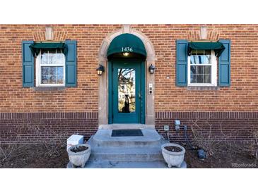 Charming brick home entrance with a glass paneled door, blue awning, and symmetrical windows at 1436 N Gilpin St # 2, Denver, CO 80218