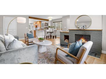 A well-decorated living room with a stone fireplace, hardwood floors, and updated kitchen in the background at 1295 Elm St, Denver, CO 80220