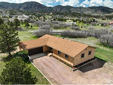 A single-story home with a brown roof and stucco exterior, nestled in a verdant landscape with mountain views at 3840 Sierra Vista Rd, Monument, CO 80132