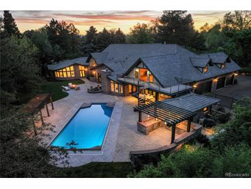 Stunning aerial view of a luxury home with a pool, outdoor kitchen, and patio at sunset at 1328 E Layton Ave, Cherry Hills Village, CO 80113