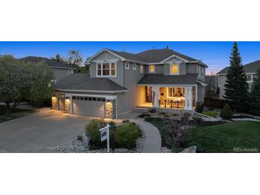 Charming two-story gray home with a well-manicured front yard, covered porch, and attached two-car garage at 9375 S Hoyt Ct, Littleton, CO 80127