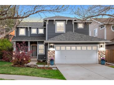 Charming two-story gray home featuring stone accents, a white garage door, and a beautifully landscaped front yard at 5910 W Sumac Ave, Littleton, CO 80123