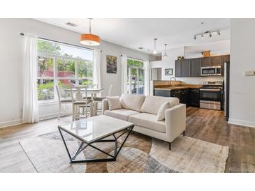 Stylish living room featuring a comfortable sofa, modern coffee table, and ample natural light from the large window at 5677 S Park Pl # A102, Englewood, CO 80111