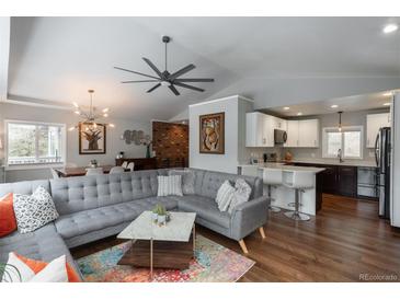 A modern living room with gray sectional sofa, hardwood floors, and an open layout to the kitchen at 5382 S Pine Rd, Evergreen, CO 80439