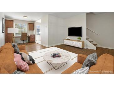 Cozy living room with an area rug, hardwood floors, and a staircase with white walls at 2872 Jasmine St, Denver, CO 80207