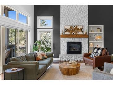 Bright living room features a stone fireplace, modern furnishings and sliding glass door to the outside deck at 30455 Telluride Ln, Evergreen, CO 80439