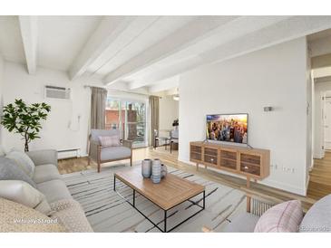 Bright living room featuring wood floors, white ceiling beams, and comfortable furniture at 100 S Clarkson St # 304, Denver, CO 80209