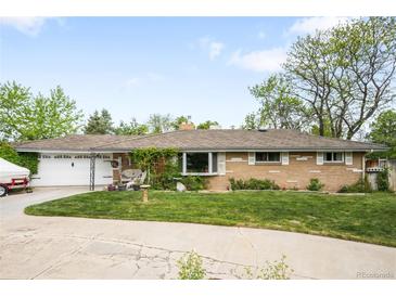 Charming ranch-style home with a well-manicured lawn, a covered porch, and an attached garage at 9045 W Ithaca Pl, Denver, CO 80235