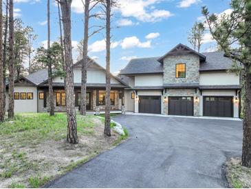 Stunning exterior of a modern luxury home featuring stone accents, a three-car garage, and a well-manicured front yard at 18330 Archers Dr, Monument, CO 80132