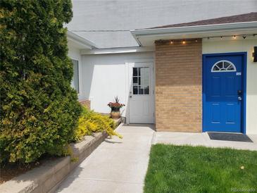 Inviting entrance with a blue door and a well-maintained walkway with lush greenery at 2860 Ames St, Wheat Ridge, CO 80214