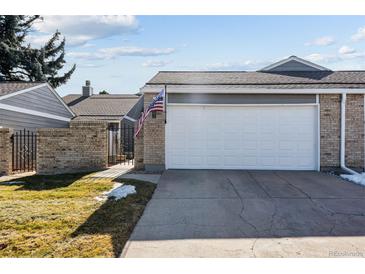 Exterior view of the home's two-car garage with an American flag in the brick facade at 7176 S Vine E Cir, Centennial, CO 80122