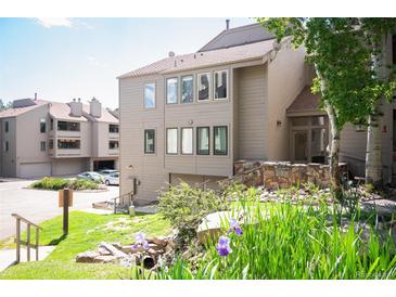 Inviting multi-level condo with a well-maintained lawn and charming landscaping with mature trees and colorful flowers at 23585 Genesee Village Rd # E, Golden, CO 80401