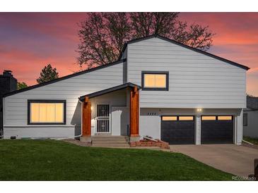 Inviting home exterior featuring a two-car garage, manicured lawn, and natural wood porch supports at dusk at 4484 S Granby Ct, Aurora, CO 80015