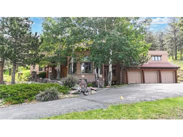Charming home exterior with mature trees and a three-car garage at 974 Spring Ranch Dr, Golden, CO 80401
