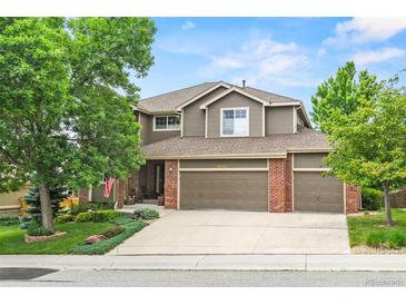 Charming two-story home with three-car garage, well-maintained lawn and brick accents at 15962 W 70Th Dr, Arvada, CO 80007