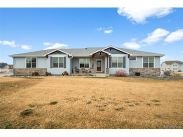 Charming single story home featuring stone accents, blue siding, and a covered front porch at 11177 E 162Nd Pl, Brighton, CO 80602