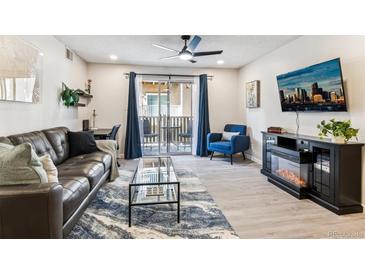 Bright living room with a ceiling fan, a fireplace, access to a balcony, and a dedicated office space at 7375 E Quincy Ave # 202, Denver, CO 80237