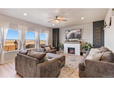 Inviting living room with a cozy fireplace, plush seating, and abundant natural light streaming through large windows at 244 Chipeta Way, Lochbuie, CO 80603