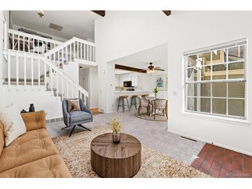 Bright living room with a staircase and view into the dining area, offering an open and inviting atmosphere at 14099 E Radcliff Cir, Aurora, CO 80015