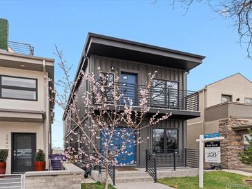 Modern two-story home featuring a unique gray facade, blue entry door, and sleek black railings on the porch and balcony at 3538 Pecos St, Denver, CO 80211