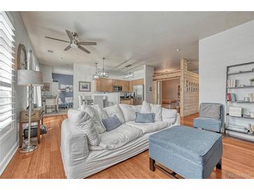 Bright living room features a comfortable white sofa, ottoman, hardwood floors, and modern ceiling fan at 5677 S Park Pl # B110, Greenwood Village, CO 80111