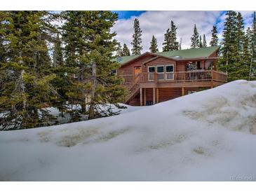 Beautiful log cabin home nestled among evergreens and covered in snow at 492 Kimmes Ln, Breckenridge, CO 80424