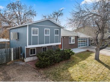 Charming two-story home boasts a blue exterior, brick accents, and a well-maintained front yard at 6252 W 70Th Pl, Arvada, CO 80003