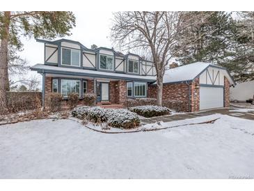 Two-story brick home with snow-covered lawn and attached garage at 1661 Red Fox Pl, Highlands Ranch, CO 80126