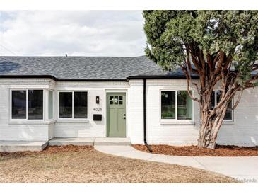 Charming white brick home with a manicured lawn, lush tree, and a welcoming green front door at 4023 E Martin Luther King Jr, Denver, CO 80207