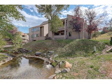 Exterior view of a condo building with a stream and landscaping at 23619 Genesee Village Rd # B, Golden, CO 80401