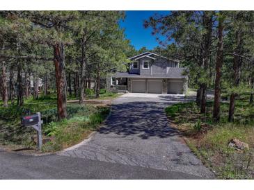 Two-story home with a three-car garage and stone accents surrounded by mature trees at 970 Bend In The Trail Rd, Monument, CO 80132