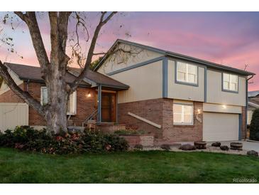 Charming two-story home with brick and siding exterior, lush landscaping, and a cozy front porch at 2013 S Holland St, Lakewood, CO 80227