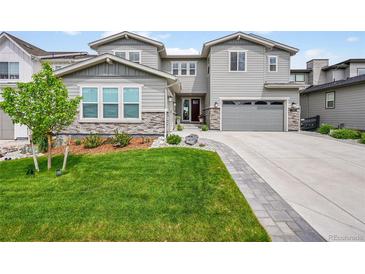 Charming two-story home with a well-manicured lawn, stone accents, and a driveway leading to an attached garage at 6912 Sunstrand Ct, Castle Pines, CO 80108