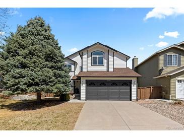 Charming two-story home featuring a large tree, gray garage door, and well-maintained front yard at 6393 Laguna Cir, Highlands Ranch, CO 80130