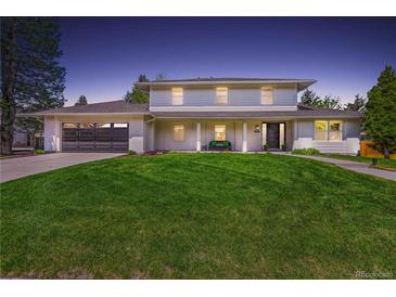 Inviting two-story home with manicured lawn, dark garage door, and a cozy front porch bench at 5853 S Havana Ct, Englewood, CO 80111