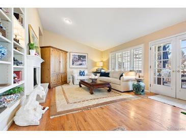 Bright living room with hardwood floors, built-in shelving, fireplace, and large windows with shutters at 4505 S Yosemite St # 106, Denver, CO 80237