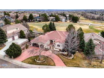 Expansive home with red tile roof, mature trees, circular driveway, and golf course community at 7022 Secrest Ct, Arvada, CO 80007