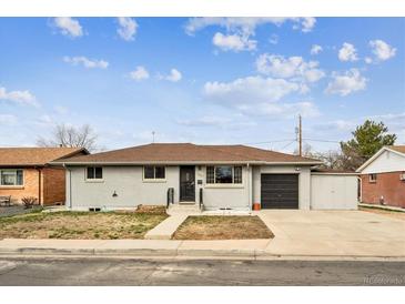 Charming single-story home featuring a grey brick exterior, a driveway, and a well-maintained front lawn at 235 N 12Th Ave, Brighton, CO 80601