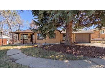Charming brick home with a covered front porch and a well-manicured lawn with mature tree at 3960 Cody St, Wheat Ridge, CO 80033