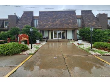 Attractive condo building featuring unique roofing, manicured shrubs, and lampposts guiding to the entryway at 8330 Zuni St # 117, Denver, CO 80221