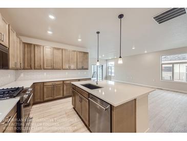 Bright kitchen features stainless steel appliances, large island with pendant lighting, and ample cabinet space at 834 W 128Th Pl, Westminster, CO 80234