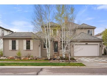 Charming two-story home with a tile roof, stone accents, and lush landscaping at 15252 W Warren Dr, Lakewood, CO 80228