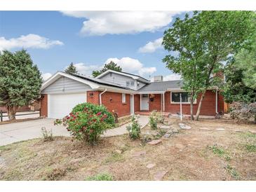 Charming red brick house featuring a well-manicured front yard and an attached garage at 206 Troy St, Aurora, CO 80011