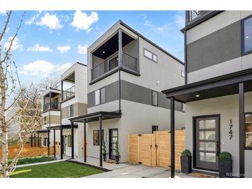 Modern townhome featuring balconies, gray and white stucco, wooden fencing, and well-manicured lawn at 1735 Lowell Blvd, Denver, CO 80204